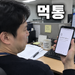 사무실 책상에서 스마트폰 화면을 보며 곤란한 표정을 짓는 남성