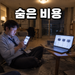 늦은 밤 거실 바닥에 앉아 휴대폰과 노트북으로 NAS 스펙을 비교해보는 남성